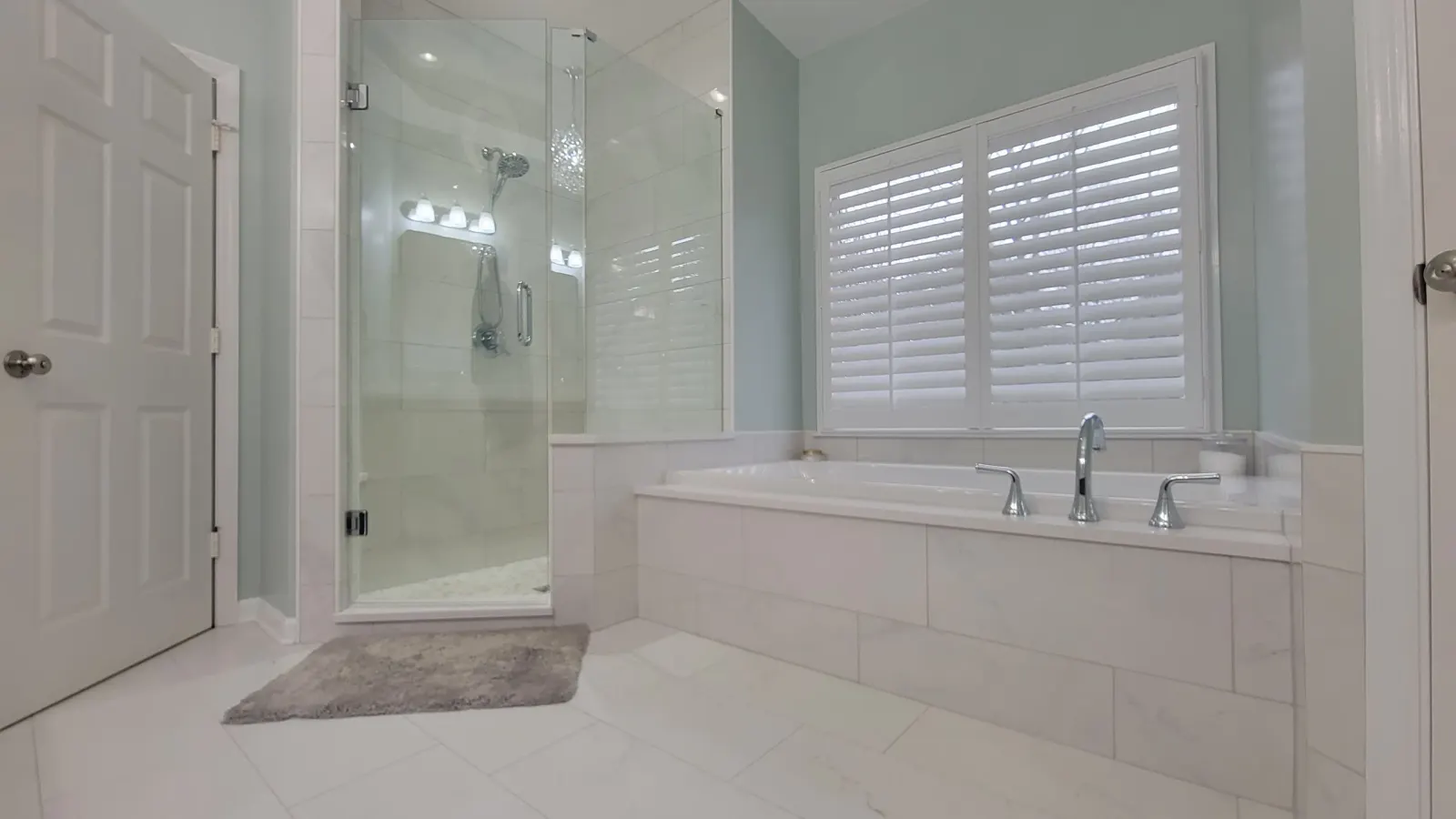 A finished Hamilton Tile bathroom remodel with a glass shower, a soaking tub, and white tile