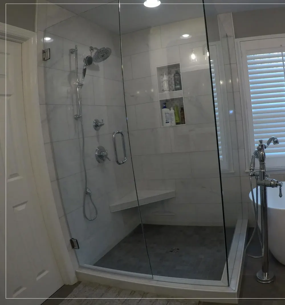 A Hamilton Tile custom shower with a corner bench, a tiled niche, and frameless glass